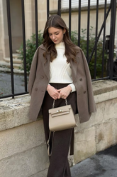 a lady in a white sweater, a brown wool wrap coat and a pair of brown pants